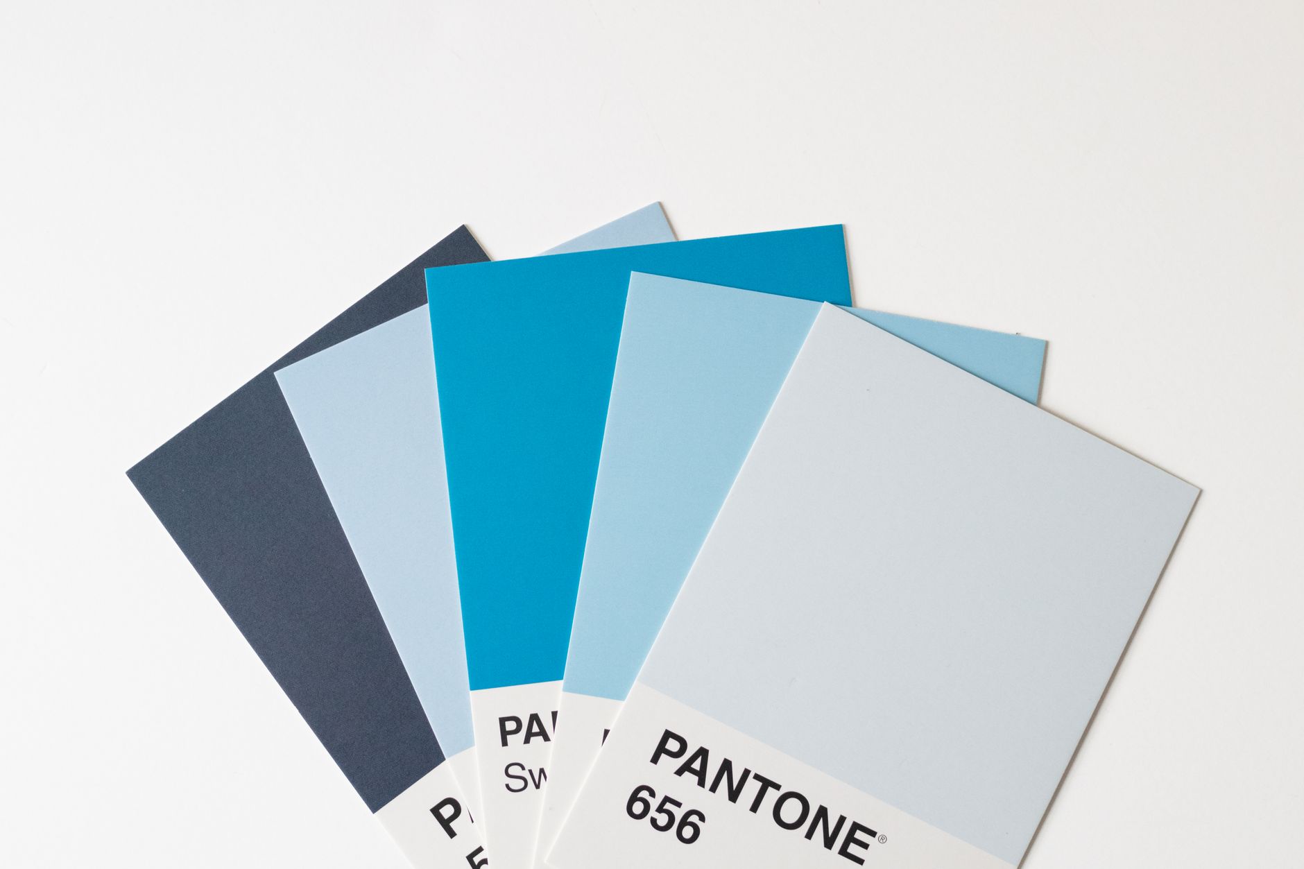 Print colour swatches next to digital design tokens on screen, illustrating the print to web design system workflow for UK publishing